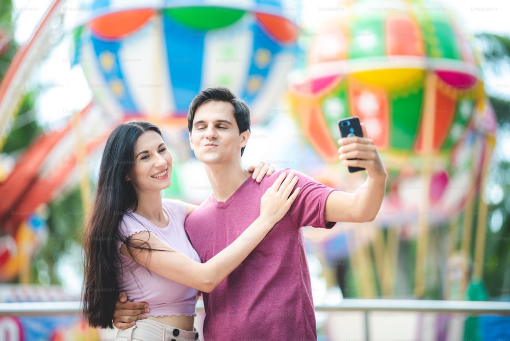 Junges Paar, das sich in einem Freizeitpark vergnügt. Dating Entspannung Liebe im Themenpark, viel Spaß und glückliches Lächeln Konzept