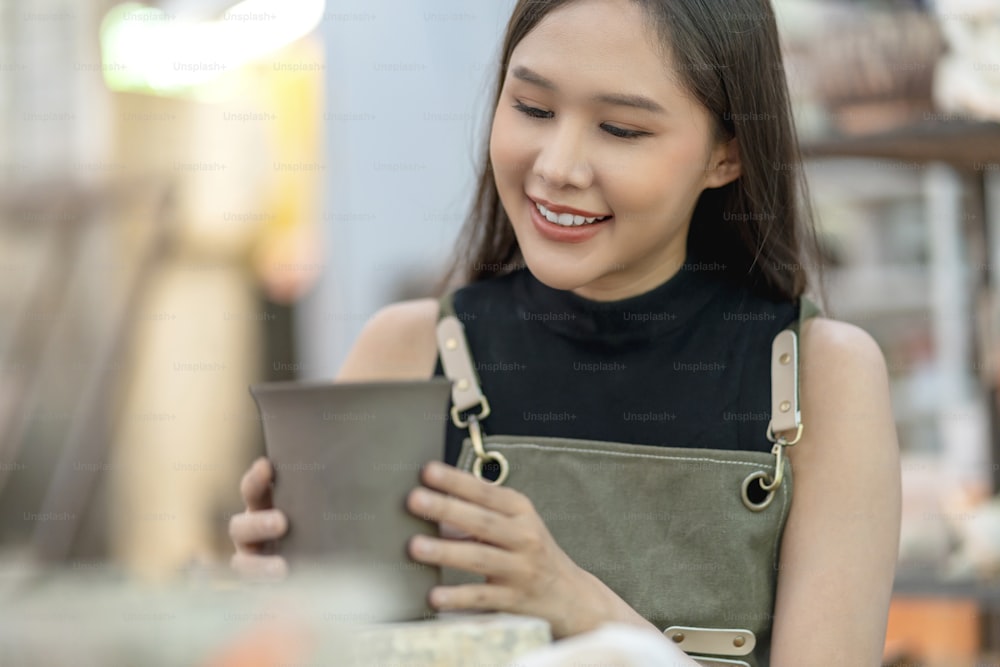 Asian Young woman female artist wear apron making clay vase bowl Beautiful young sculptor creates a clay art vase in home studio warehouse,Ceramist artist female work in studio