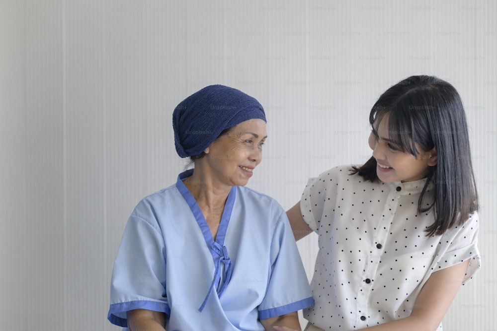 Mulher paciente com câncer usando lenço na cabeça e sua filha de apoio no hospital, saúde e conceito de seguro.