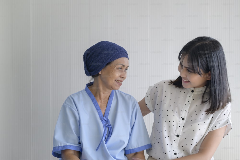 Cancer patient woman wearing head scarf and her supportive daughter in hospital, health and insurance concept.