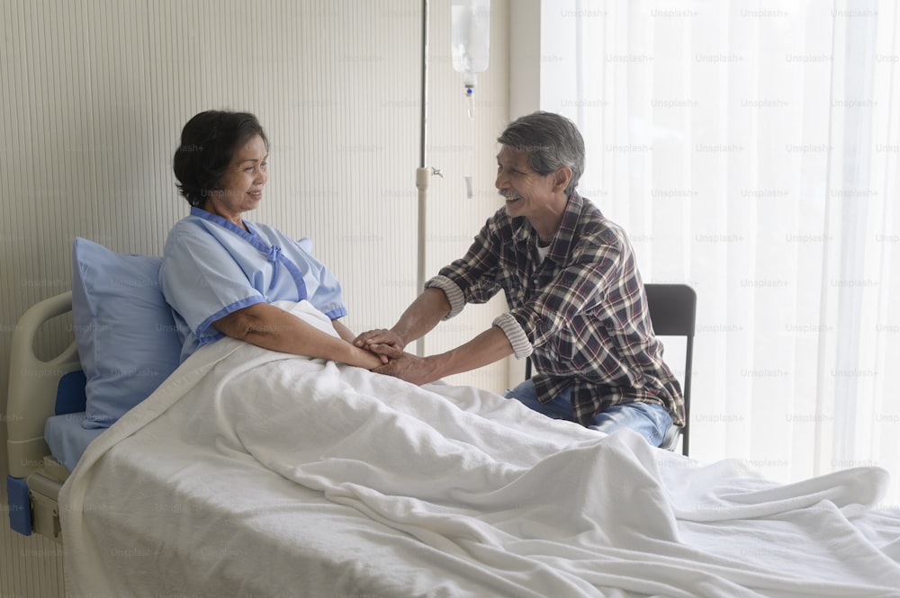 Un anciano visitando a una anciana paciente en el hospital, la atención médica y el concepto médico