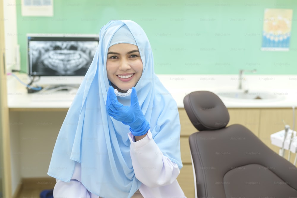 歯科医院でインビザラインを装着する若いムスリム女性歯科医、歯の検診と健康な歯のコンセプト