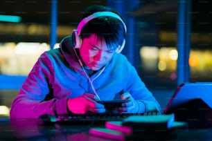 asian male esports gamer playing online sport leagues multiplayer game via smartphone with exited and cheerful emotion,asian male wear headset playing smartphone game online together with friends