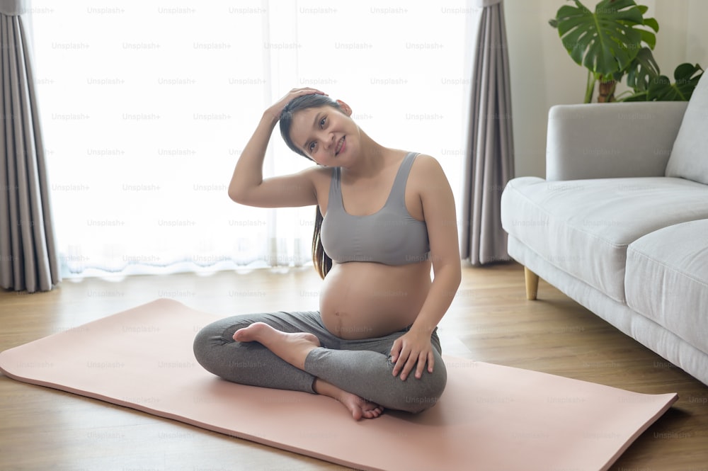 Young pregnant woman doing yoga at home, healthcare and pregnancy care concept