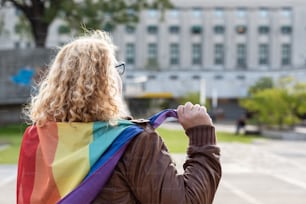 Vista posteriore o un'attivista lesbica sotto la bandiera arcobaleno LGBT. Concetto di orgoglio. Orgoglio