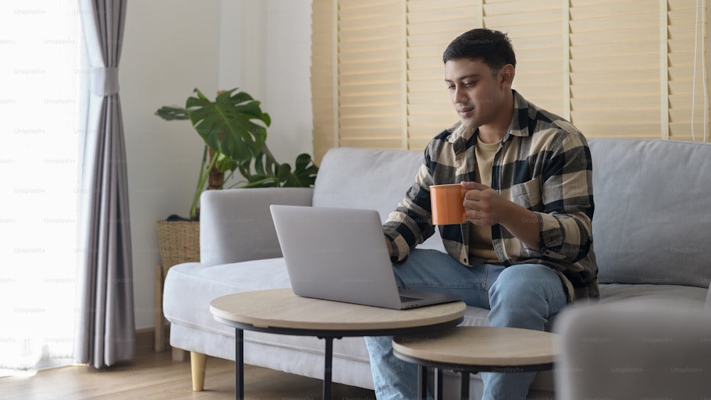 Young man working with laptop in living room at home