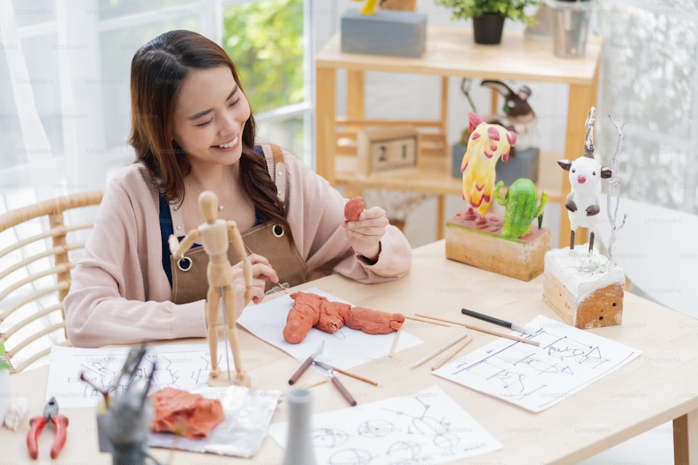 Asian Female artist an arttoys clay sculpture spend weekend day for her hobby clay scuplt properly define the form face anatomy, while making the clay statue at home studio casual lifestyle at home