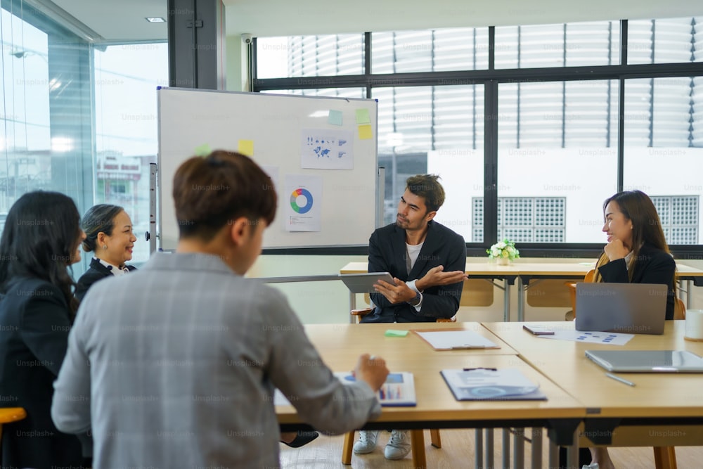 Treffen asiatischer Geschäftsleute, die sich der Arbeit verschrieben haben. Kreatives Business-Team sitzt zusammen im Büro.