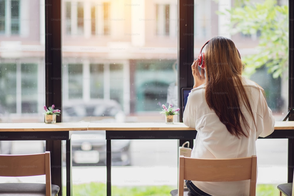 Asian woman enjoy listening to music and laptop computer in the morning.