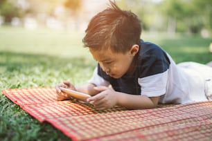 Niño jugando con un teléfono inteligente en el parque.