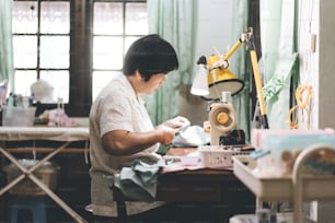 재봉틀로 천을 만드는 동남아시아 노인들. 베이비 붐 세대는 성숙한 재택 근무 개념입니다. 솔직한 초상화의 삶의 순간은 진정한 사람들입니다.