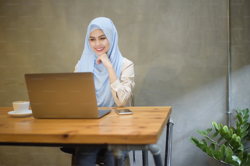 Muslim woman with hijab is working with laptop computer in coffee shop