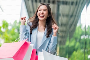 beautiful asia woman female pleased positive casual shopping hand hold paper bags happy woman enjoy purchase cloths shopping buy sales discount at center mall store shopfront corridor department store