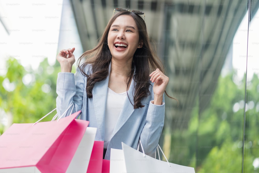 beautiful asia woman female pleased positive casual shopping hand hold paper bags happy woman enjoy purchase cloths shopping buy sales discount at center mall store shopfront corridor department store