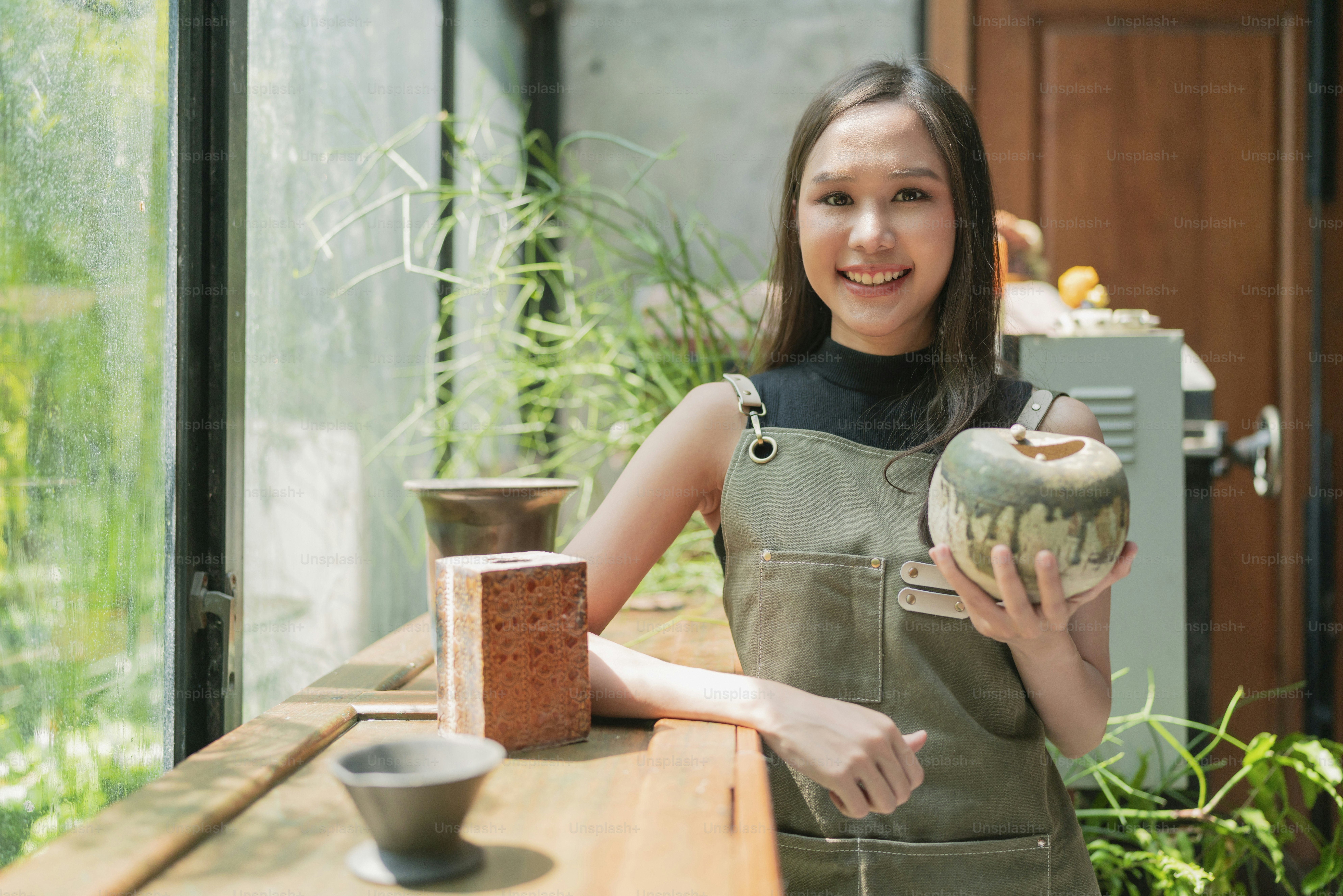 アジアの女性の大人の陶芸家デザイナーは、自宅の工場スタジオで笑顔の