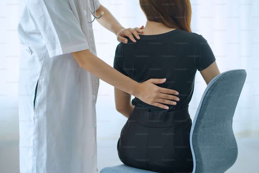 Physiotherapeut kümmert sich um einen Patienten mit Rückenschmerzen in einer Klinik.