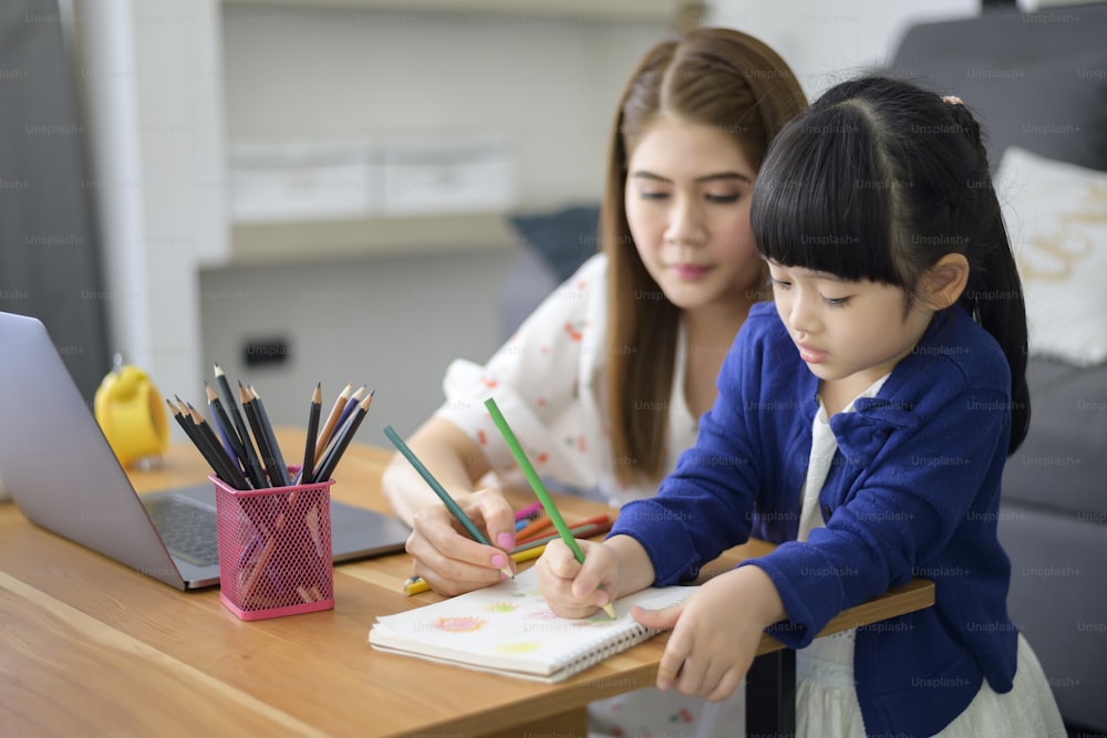 Asian Happy Mama und Tochter benutzen Laptop für das Lernen online über das Internet zu Hause. E-Learning-Konzept während der Quarantänezeit.