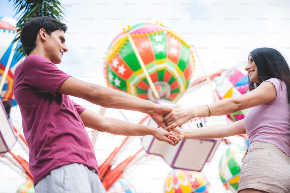 young couple holding hand at an amusement park, happy to travel in theme park