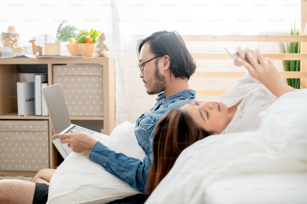 Asiatico coppia amante attività casuale in camera da letto mano mano laptop e smartphone camera da letto sfondo interno