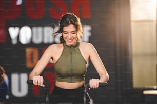 exercício da mulher jovem com equipamento de máquina de bicicleta no ginásio de fitness, treinamento de bicicleta ativo para cardio saudável e corpo, estilo de vida esportivo