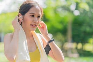 asian female woman sportwear doing morning jogging holding headphones Putting earphones before exercise ,Happy young woman listening music outdoors in city park garden morning fitness healthy life