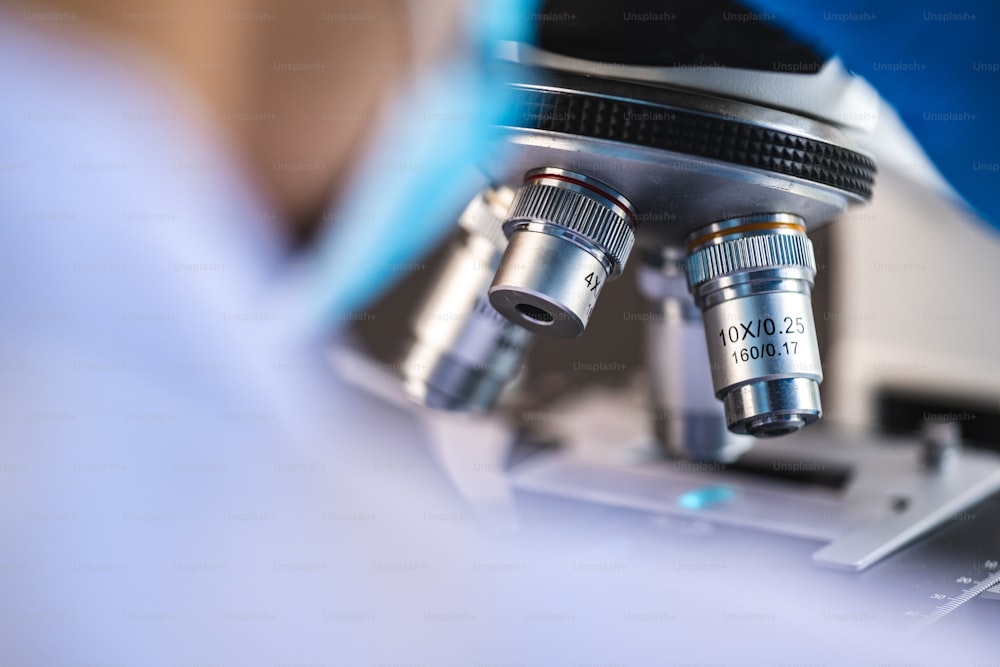 化学医学実験室で顕微鏡を使用する専門の研究員の集中、バイオテクノロジーまたは生物学実験用の医学技術機器を扱う技術者