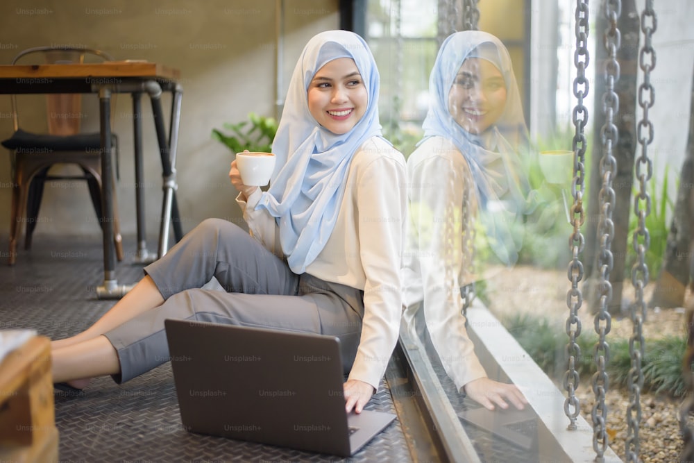 Muslim woman with hijab is working with laptop computer in coffee shop