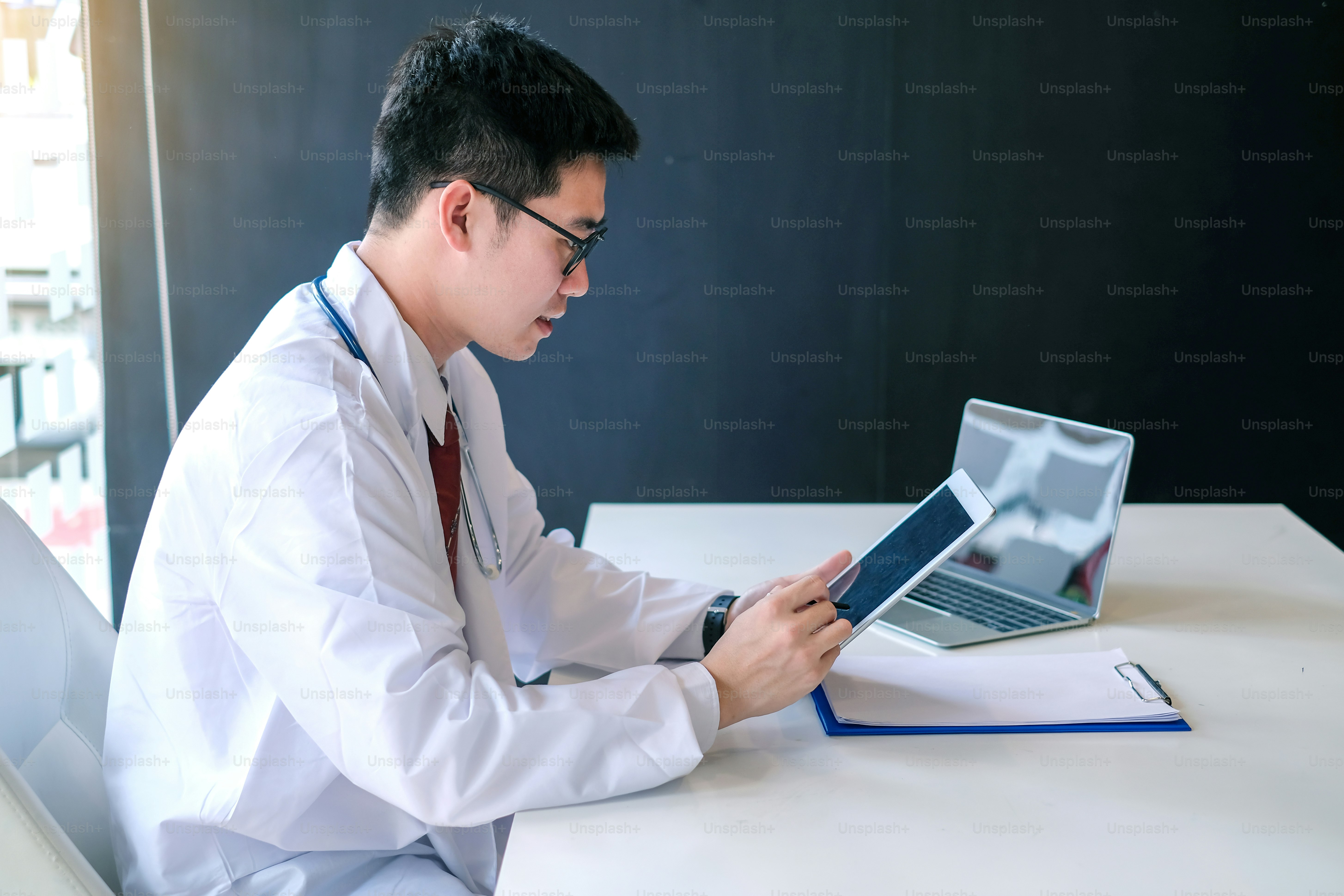 Doctor working with laptop computer and see patient record in document ...