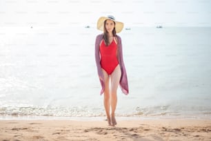 Beautiful woman in red swimsuit is walking from the sea, Summer Concept