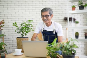 happy senior asian retired man with laptop  is relaxing  and enjoying  leisure activity in garden at home.