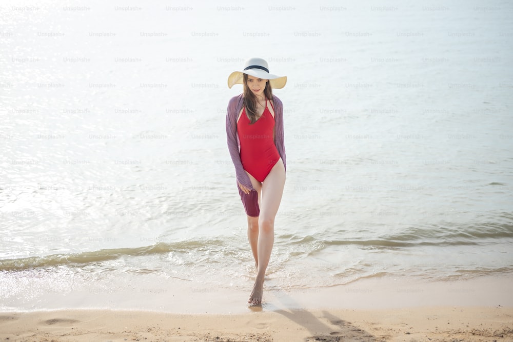 Schöne Frau im roten Badeanzug geht vom Meer aus, Summer Concept
