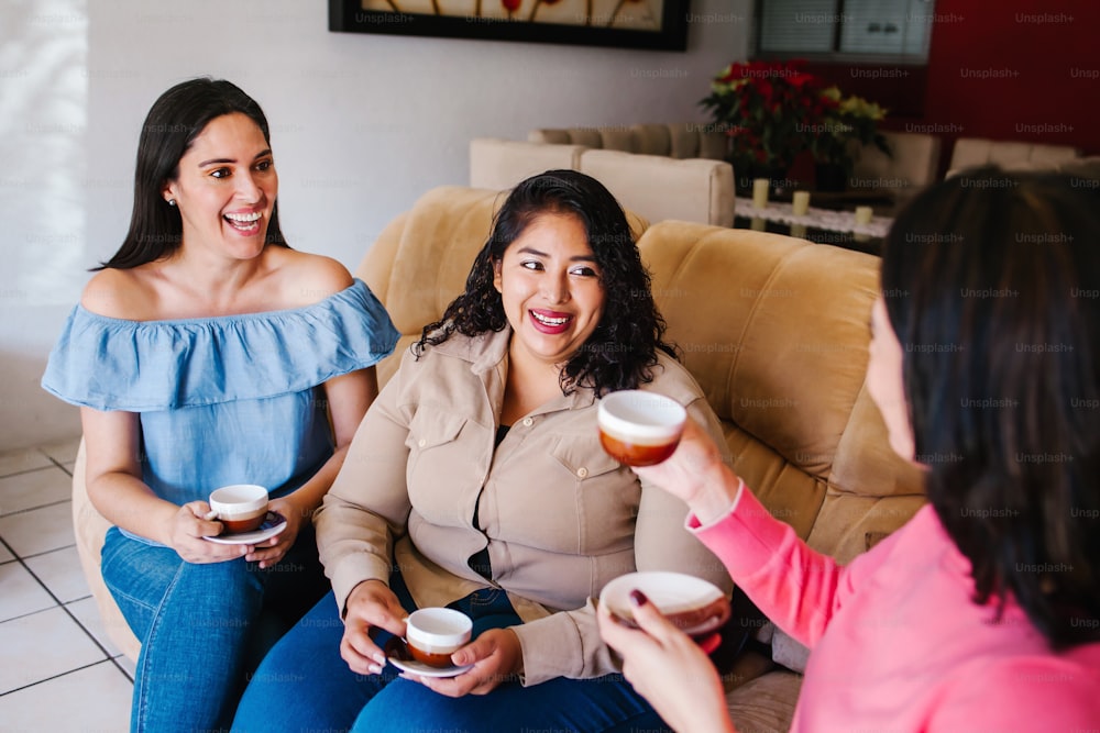 Chicas latinas divirtiéndose en casa, riendo y tomando café en la ciudad de México