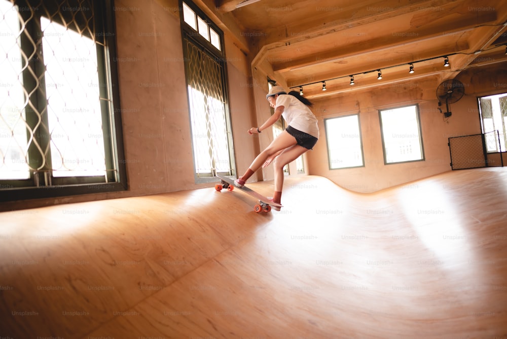 skater woman person playing skateboard in sport gym, young Asian woman are happy and fun with skateboarding lifestyle in city, teenage hipster female trendy fashion