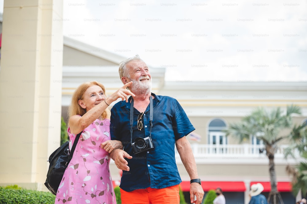 Senior couple enjoying and happy to travel and playing at an amusement theme park, concept of love and happy with old 60's senior people