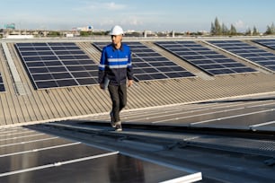 Portrait d’ingénieur asiatique sur le fond du domaine des panneaux solaires photovoltaïques, des cellules solaires sur le toit, de l’usine.