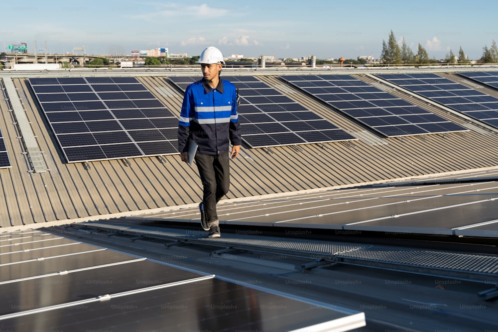 옥상 공장에 있는 태양광 태양 전지판 태양 전지의 배경 필드에 있는 아시아 엔지니어의 초상화.