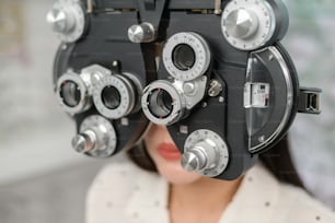 Eine junge Kundin wird visueller Test mit Bifokal-Optometrie-Sehmessgerät von Augenarzt in optischem Zentrum, Augenpflegekonzept untersucht.