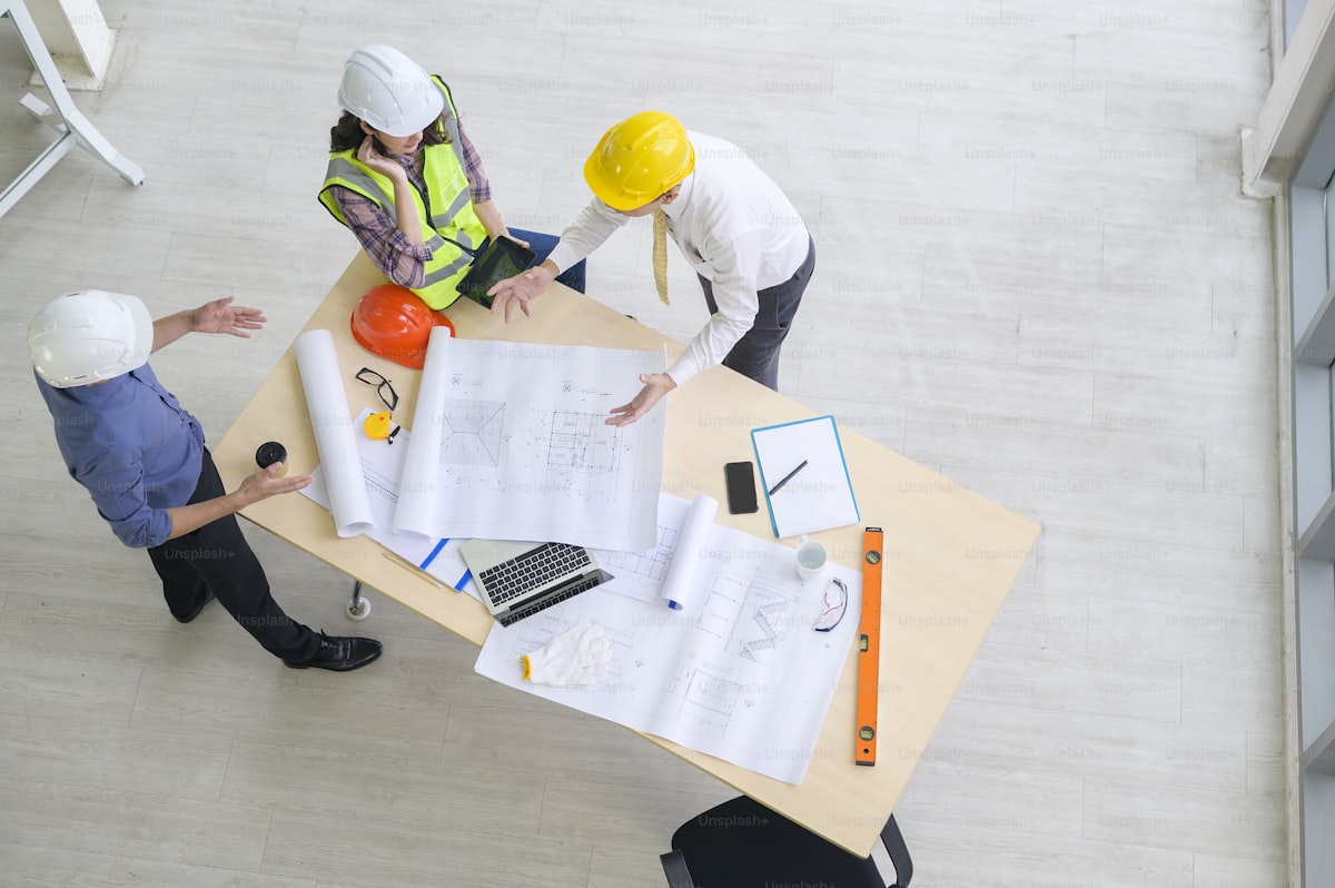 Construction team reviewing blueprints and plans around a table in a commercial office