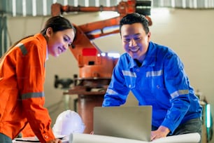 engineer cooperation Two asian male and female technician maintenance inspect relay robot system with tablet laptop to control quality operate process work heavy industry 4.0 manufacturing factory
