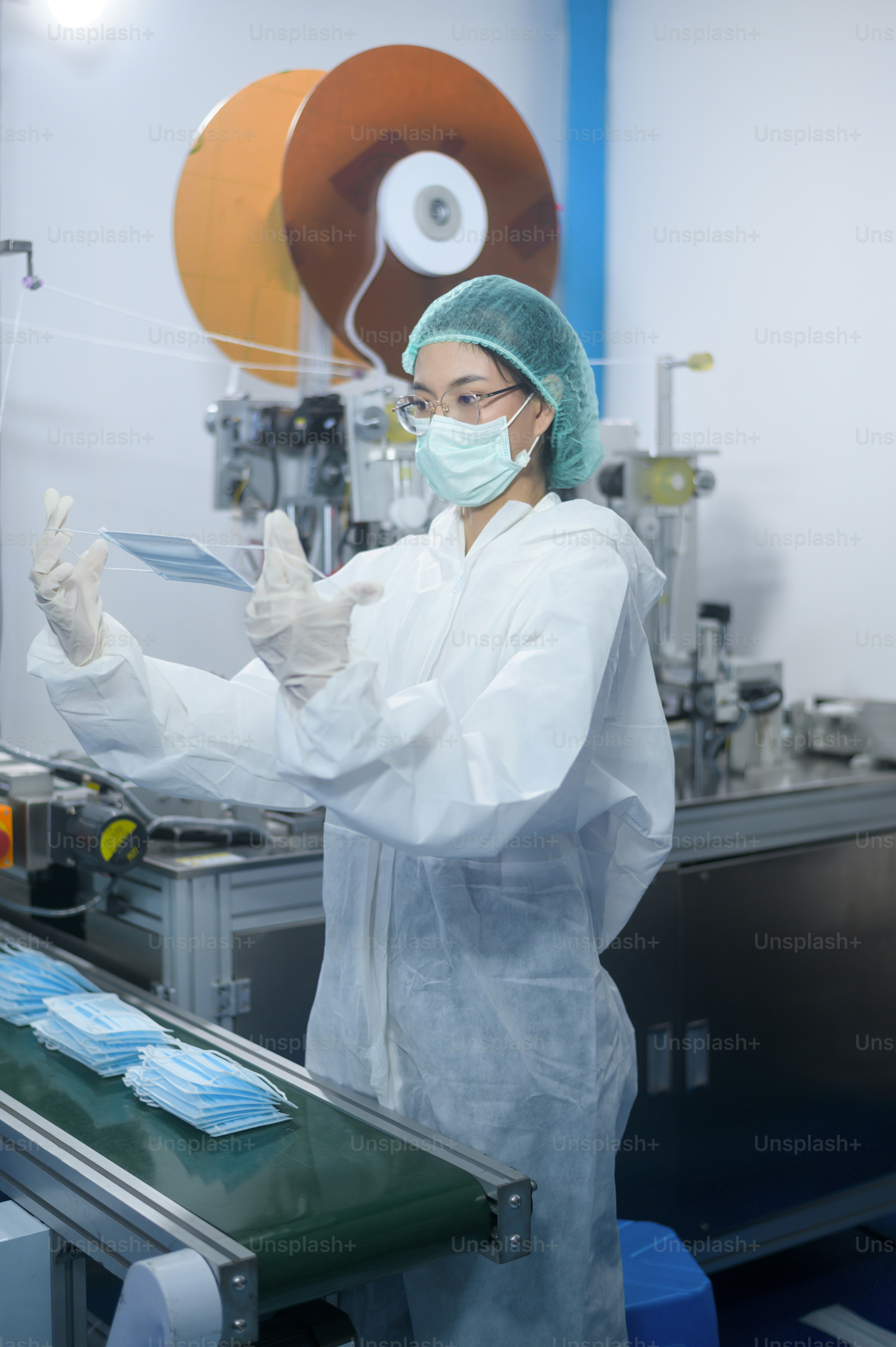 Workers producing surgical mask in modern factory, Covid-19 protection and medical concept.