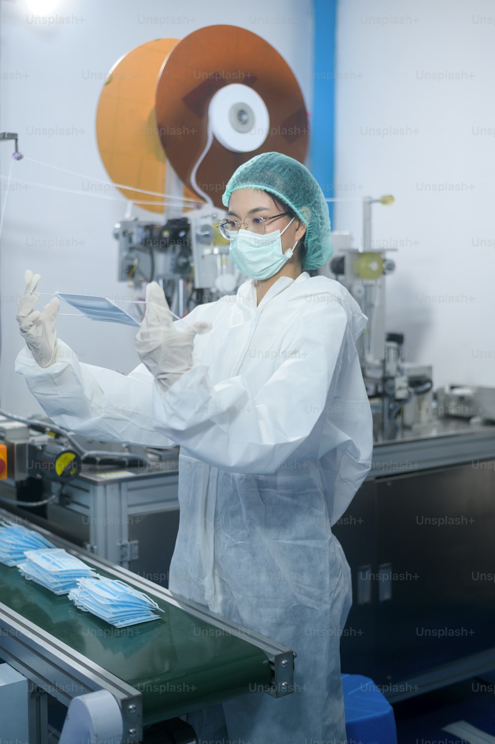 Trabalhadores produzindo máscara cirúrgica em fábrica moderna, proteção contra a Covid-19 e conceito médico.