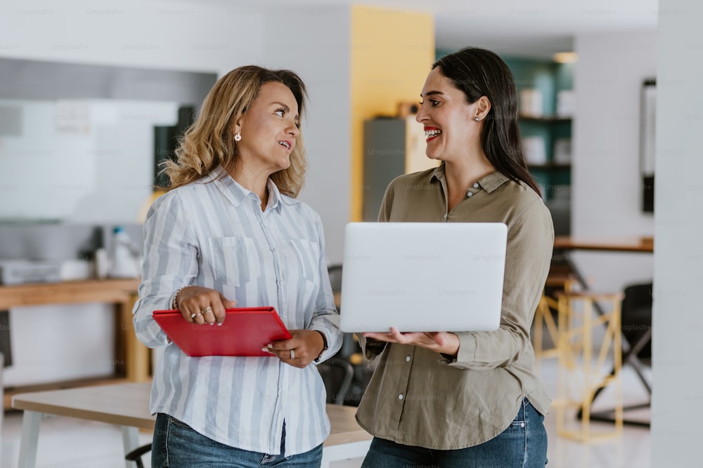 Two latin business woman middle age, talking and advising each other at the office in Mexico Latin America