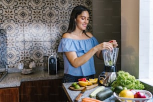 Latin Woman making green smoothie or Detox juice in kitchen at Home in healthy eating concept in Mexico