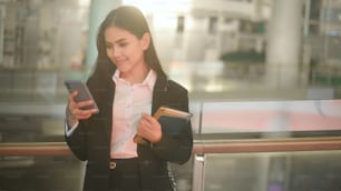 검은 양복을 입은 젊은 비즈니스 여성은 도시에서 비즈니스 라이프 스타일 컨셉을 스마트 폰을 사용하고 있습니다.