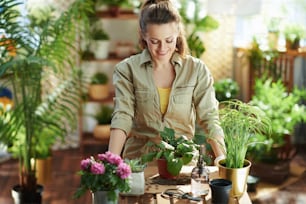 Green home. happy modern 40 years old housewife in white rubber gloves with potted plant do gardening in the modern house in sunny day.