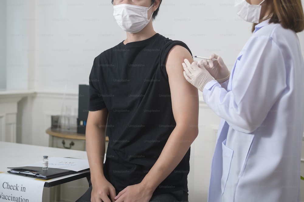 A female doctor injecting covid-19 vaccine to patient arm, covid-19 vaccination and health care concept