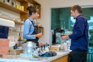 Junge serviceorientierte Barista-Frau mit Kundin im Café