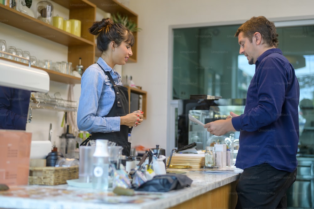 Junge serviceorientierte Barista-Frau mit Kundin im Café