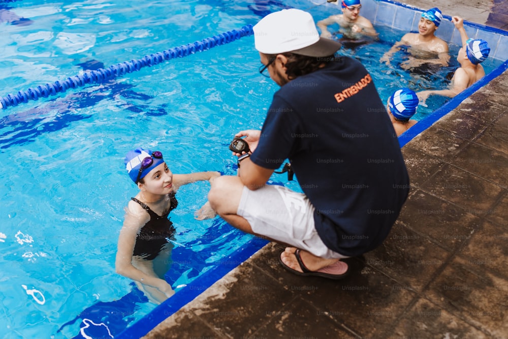 Latin swimming man trainer talking some advices to teenagers swimmers students at the pool in Mexico Latin America