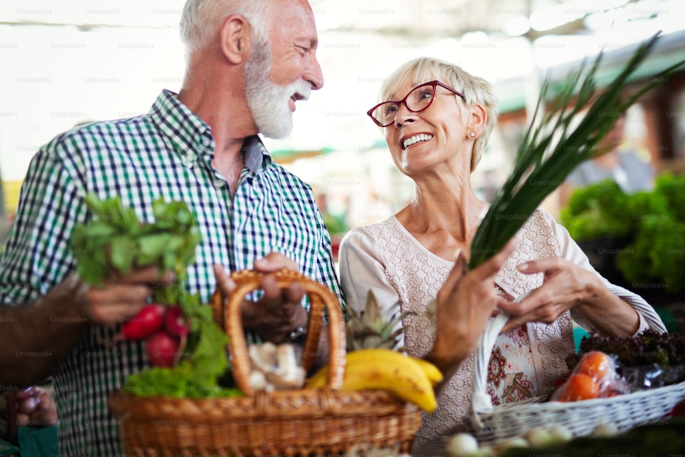 Couple de personnes âgées heureuses avec panier sur le marché. Alimentation saine.